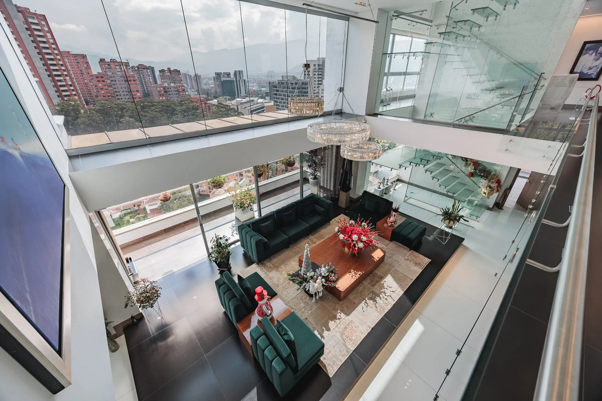 Moderna sala con ventanales de piso a techo y salida directa a una terraza con vista 360°, en apartamento de lujo en El Poblado Medellín.