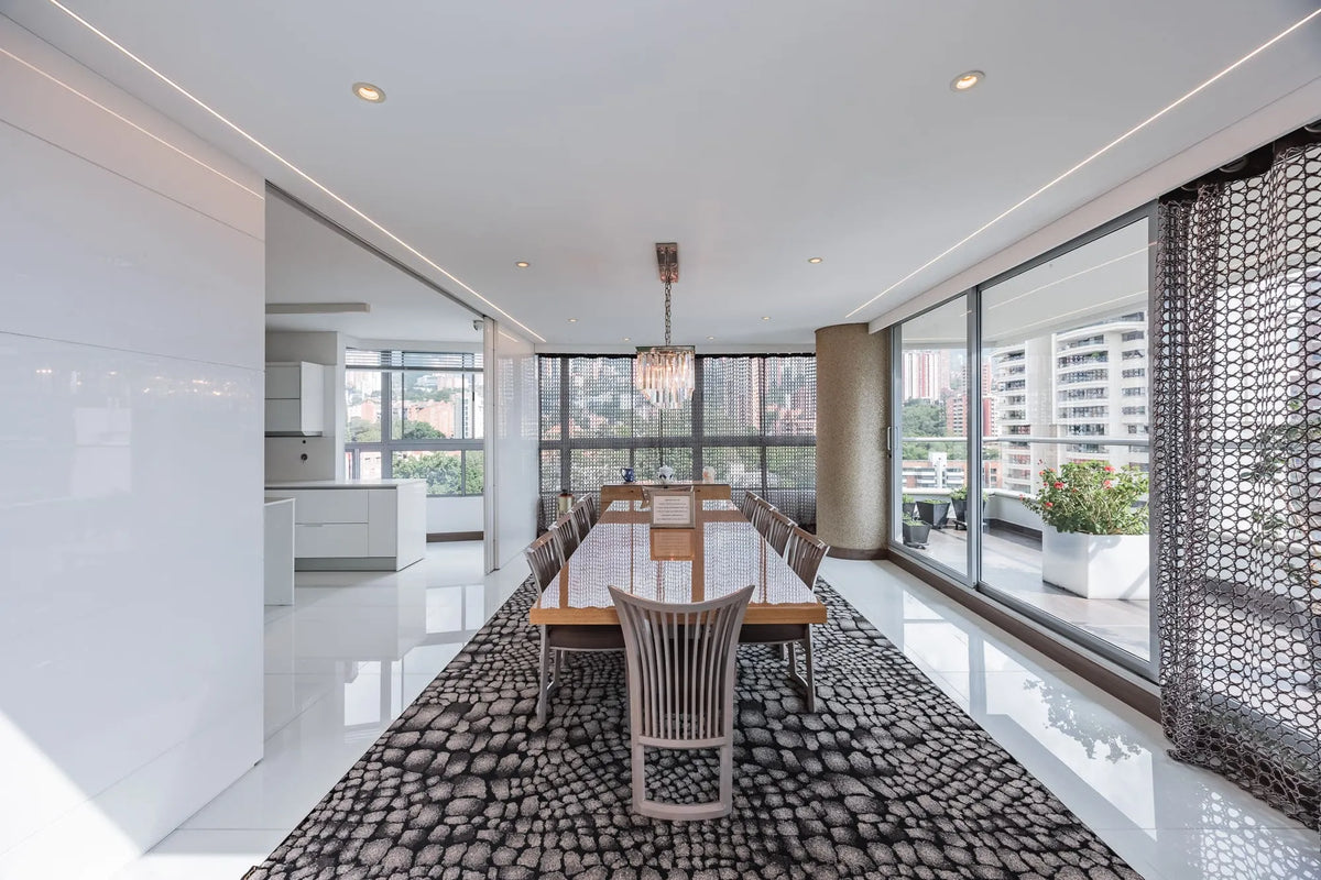 Moderna sala con ventanales de piso a techo y salida directa a una terraza con vista 360°, en apartamento de lujo en El Poblado Medellín.