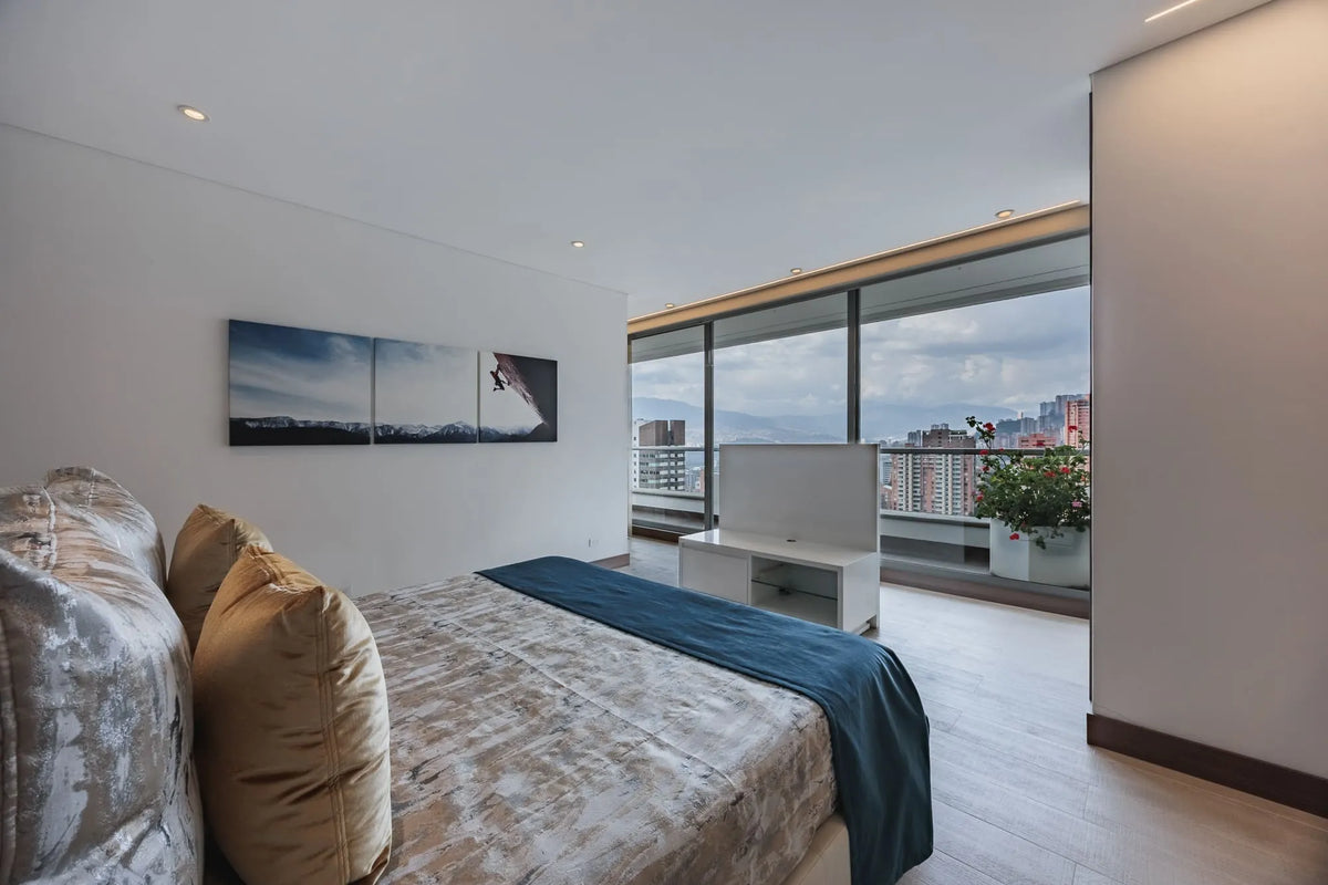 Dormitorio principal con acceso a balcón privado y vista al sur de Medellín, dentro de un apartamento de 5 habitaciones en El Poblado.