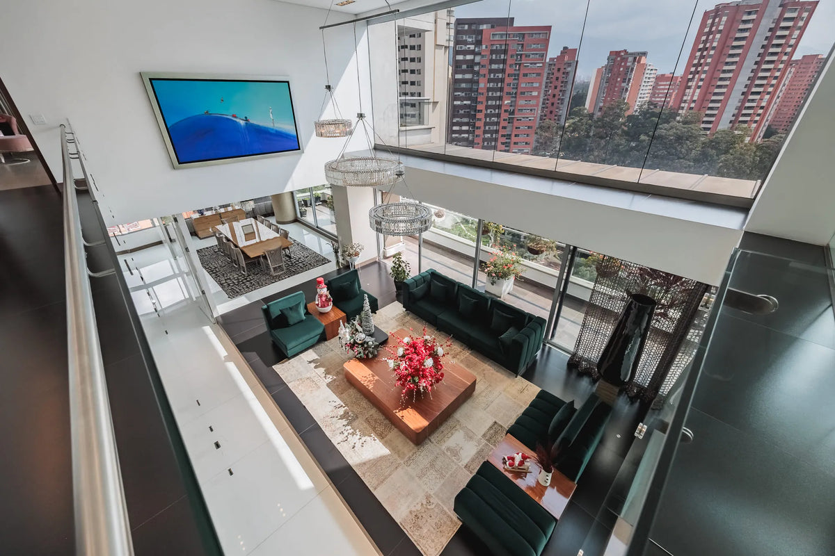 Moderna sala con ventanales de piso a techo y salida directa a una terraza con vista 360°, en apartamento de lujo en El Poblado Medellín.