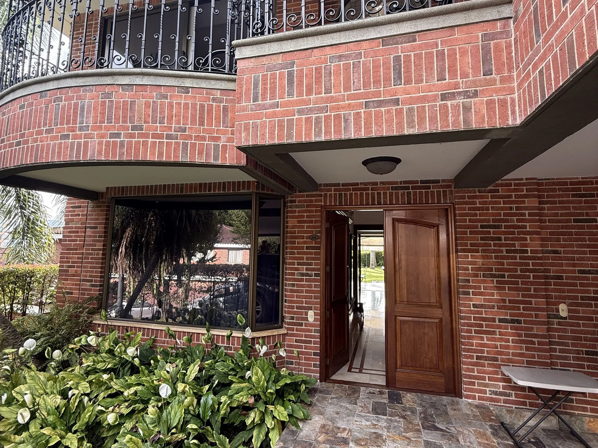 Fachada de casa en El Poblado con amplio lote y jardines.