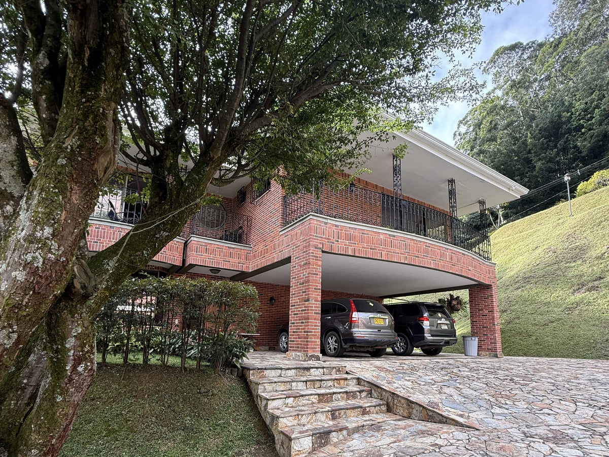 Fachada de casa en El Poblado con amplio lote y jardines.