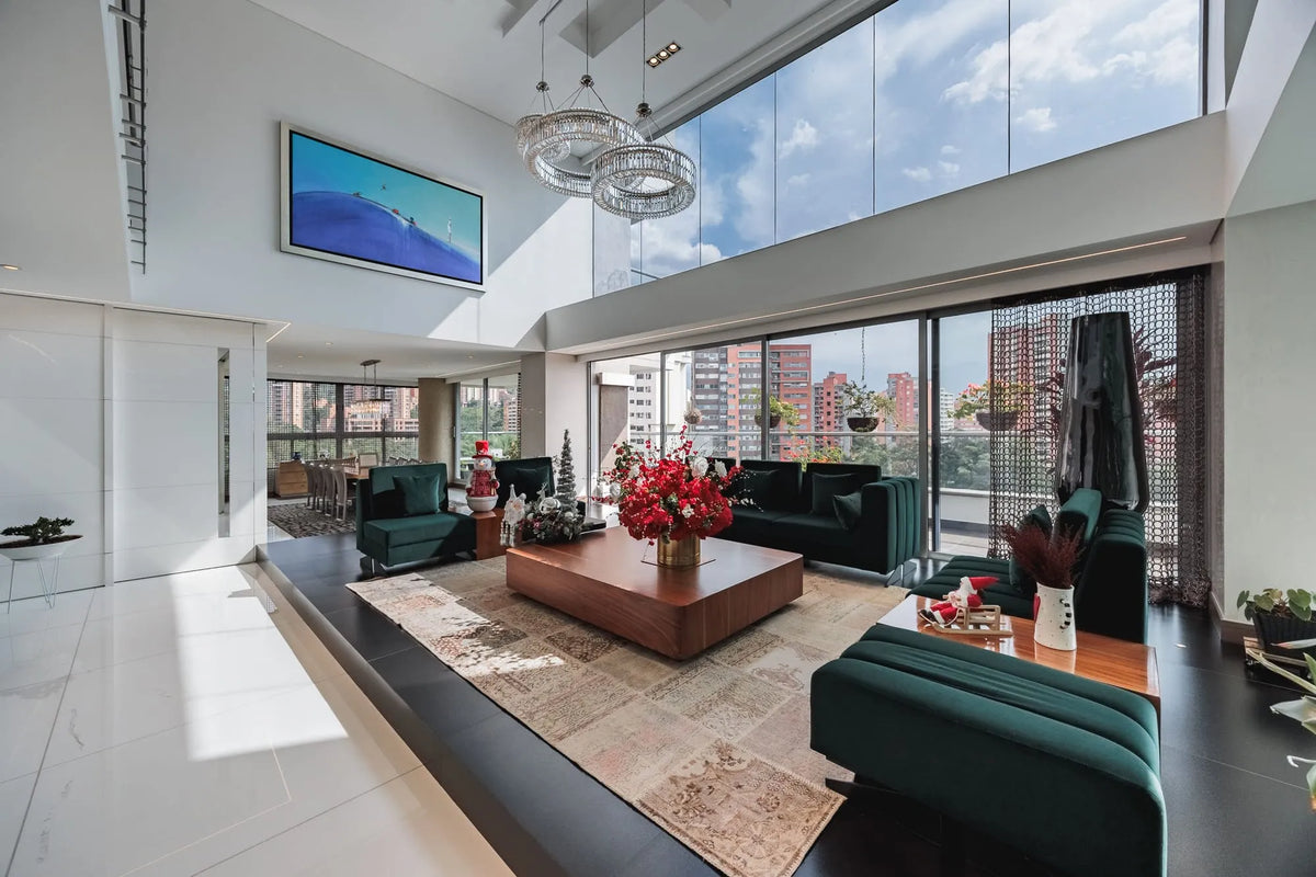 Moderna sala con ventanales de piso a techo y salida directa a una terraza con vista 360°, en apartamento de lujo en El Poblado Medellín.