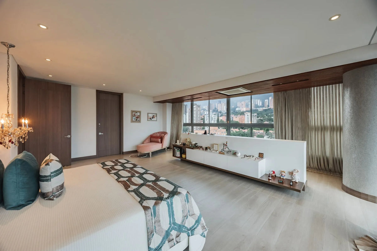 Dormitorio principal con acceso a balcón privado y vista al sur de Medellín, dentro de un apartamento de 5 habitaciones en El Poblado.