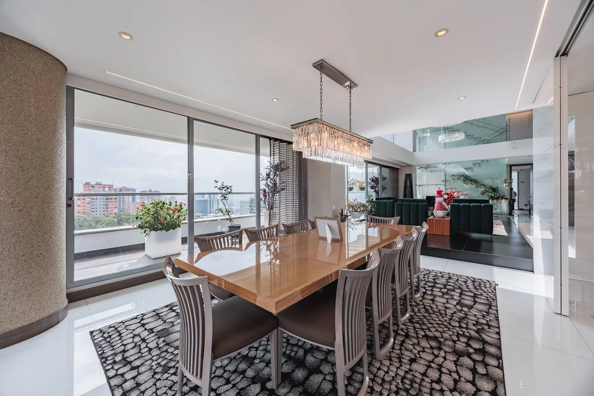 Moderna sala con ventanales de piso a techo y salida directa a una terraza con vista 360°, en apartamento de lujo en El Poblado Medellín.