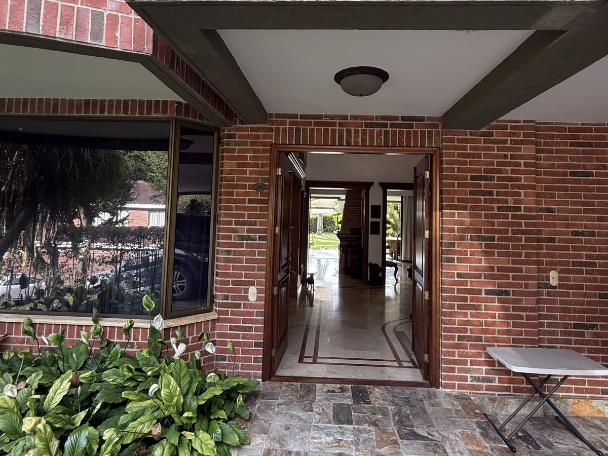 Fachada de casa en El Poblado con amplio lote y jardines.