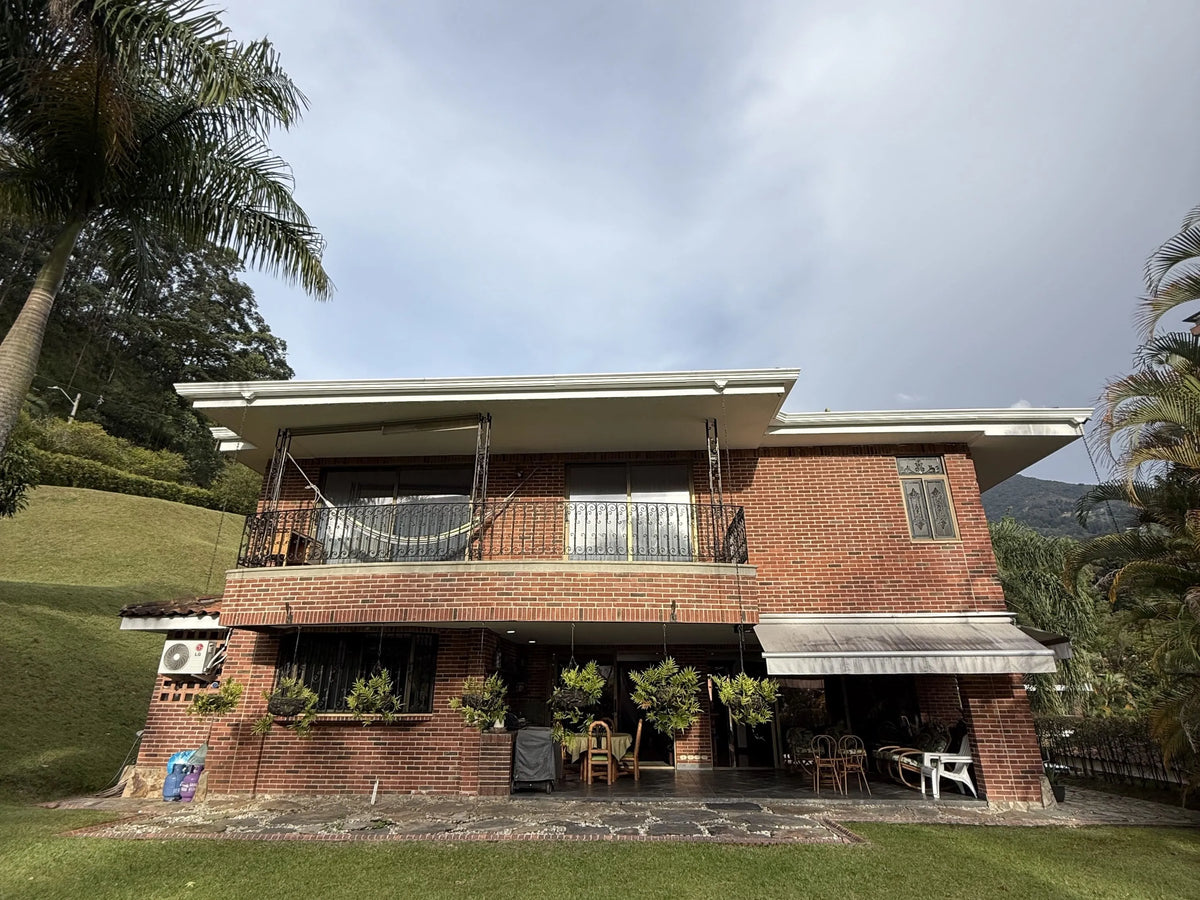 Fachada de casa en El Poblado con amplio lote y jardines.